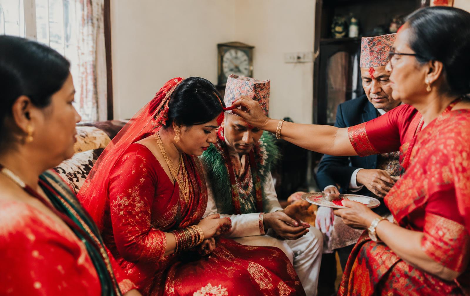 Newlywed Nepali couple receiving tika blessings from family elders at home